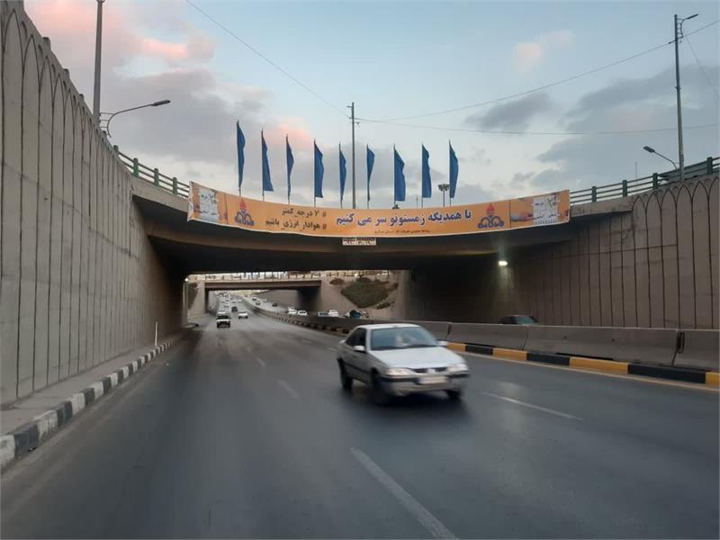 اکران بنر صرفه‌جویی در مصرف گاز بر عرشه پل زیرگذر میدان فراهان اراک